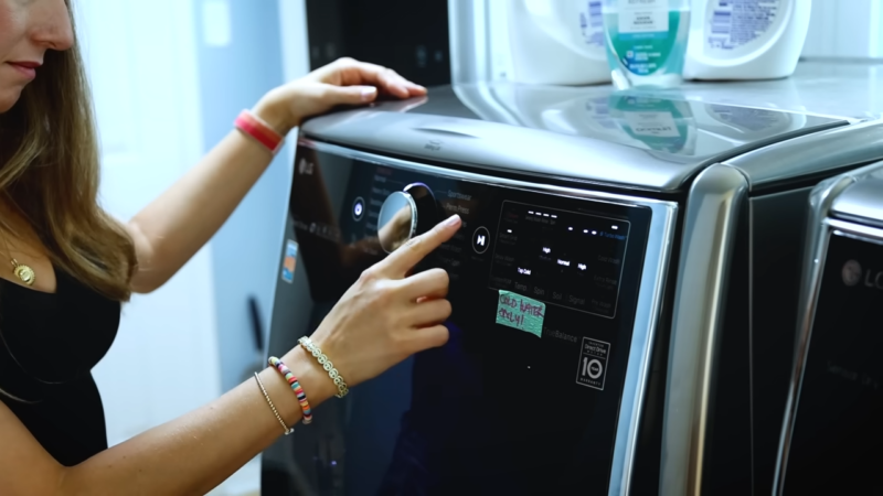 A Person Is Selecting a Wash Cycle on A Washing Machine, Likely Preparing to Use a Double Rinse Cycle