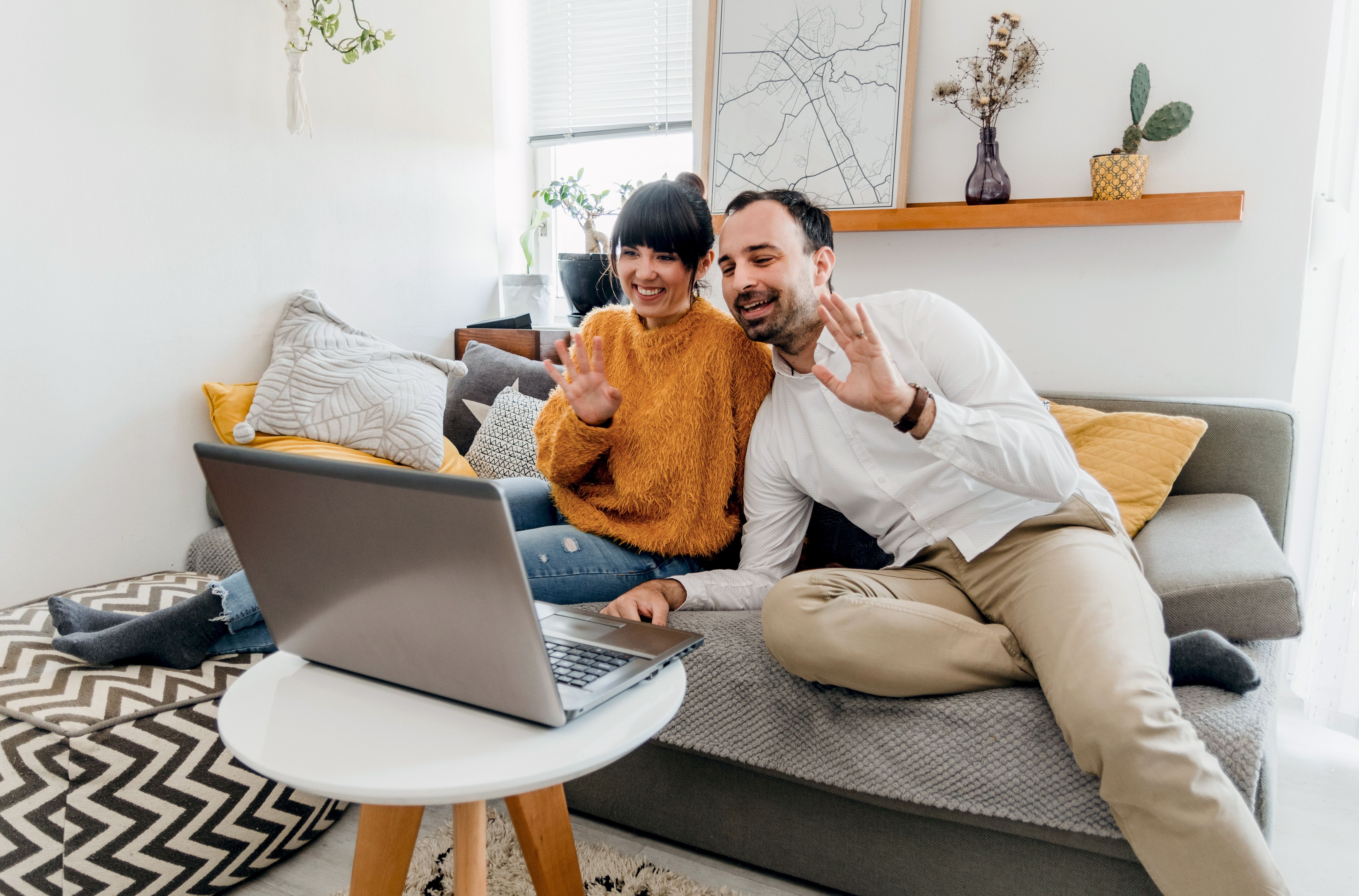 Happy couple on a couch sharing a video call, illustrating digital intimacy