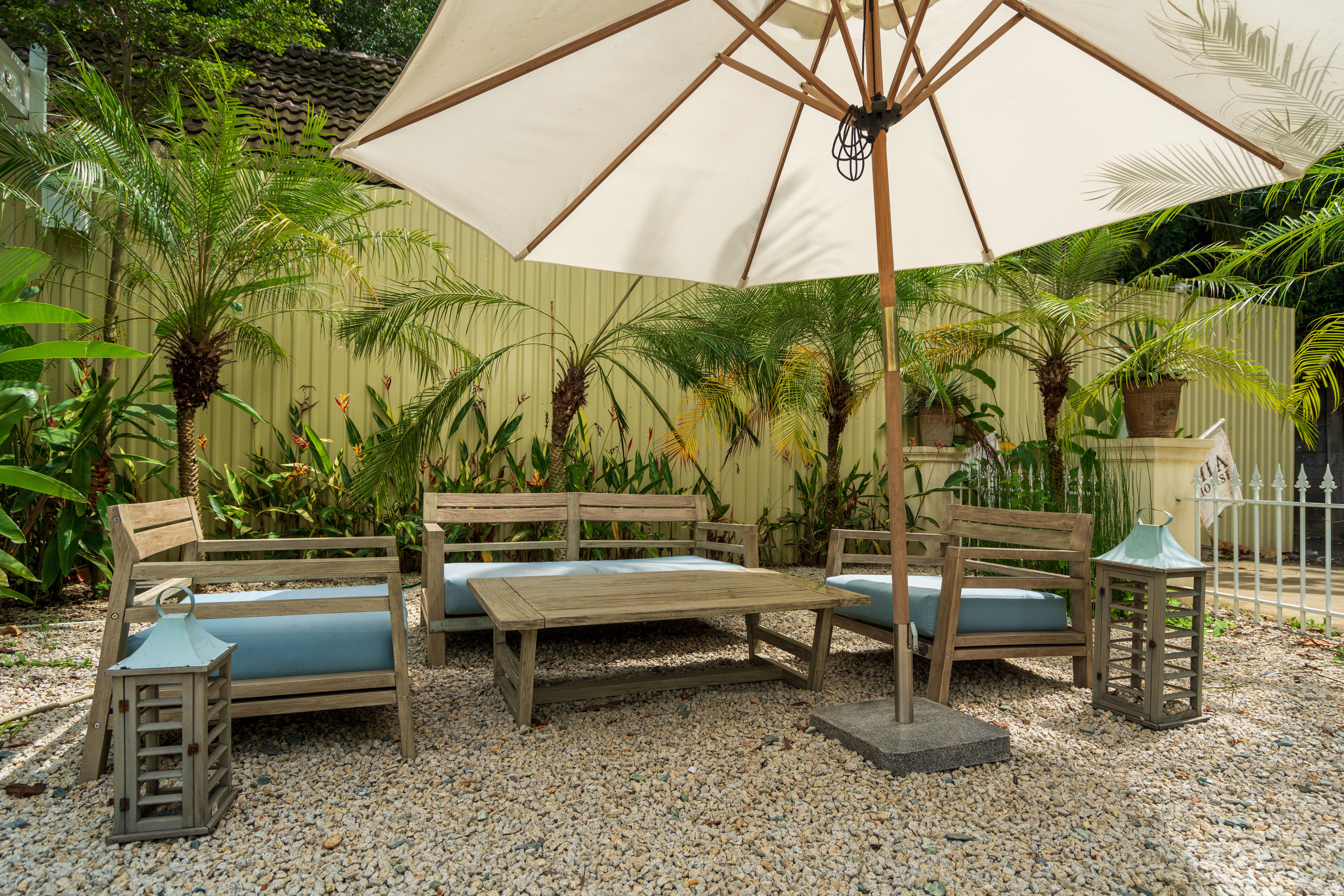 Cozy garden patio with wooden table, chairs and umbrella surrounded by lush greenery