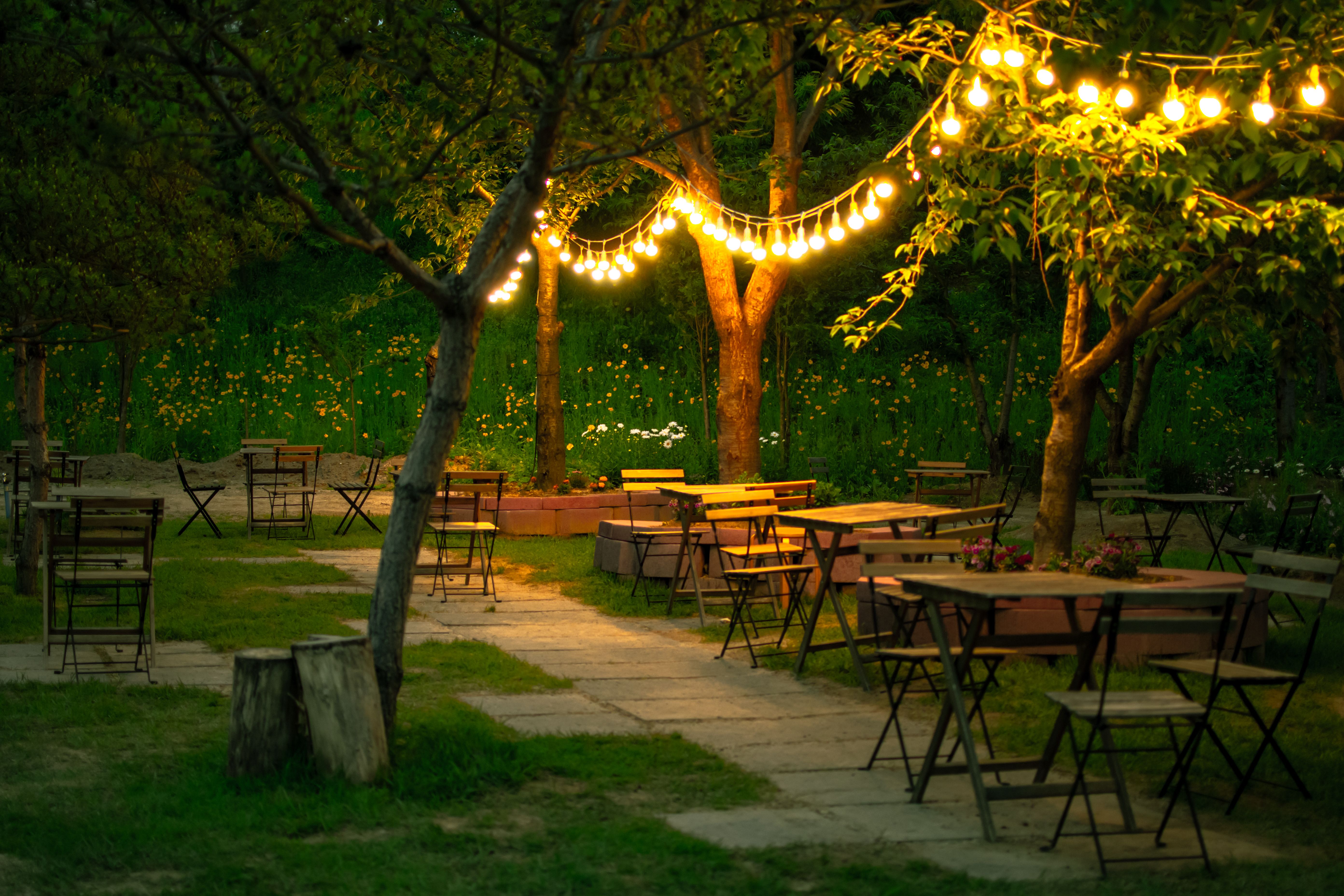Cozy garden dining area with wooden tables and string lights for evening gatherings