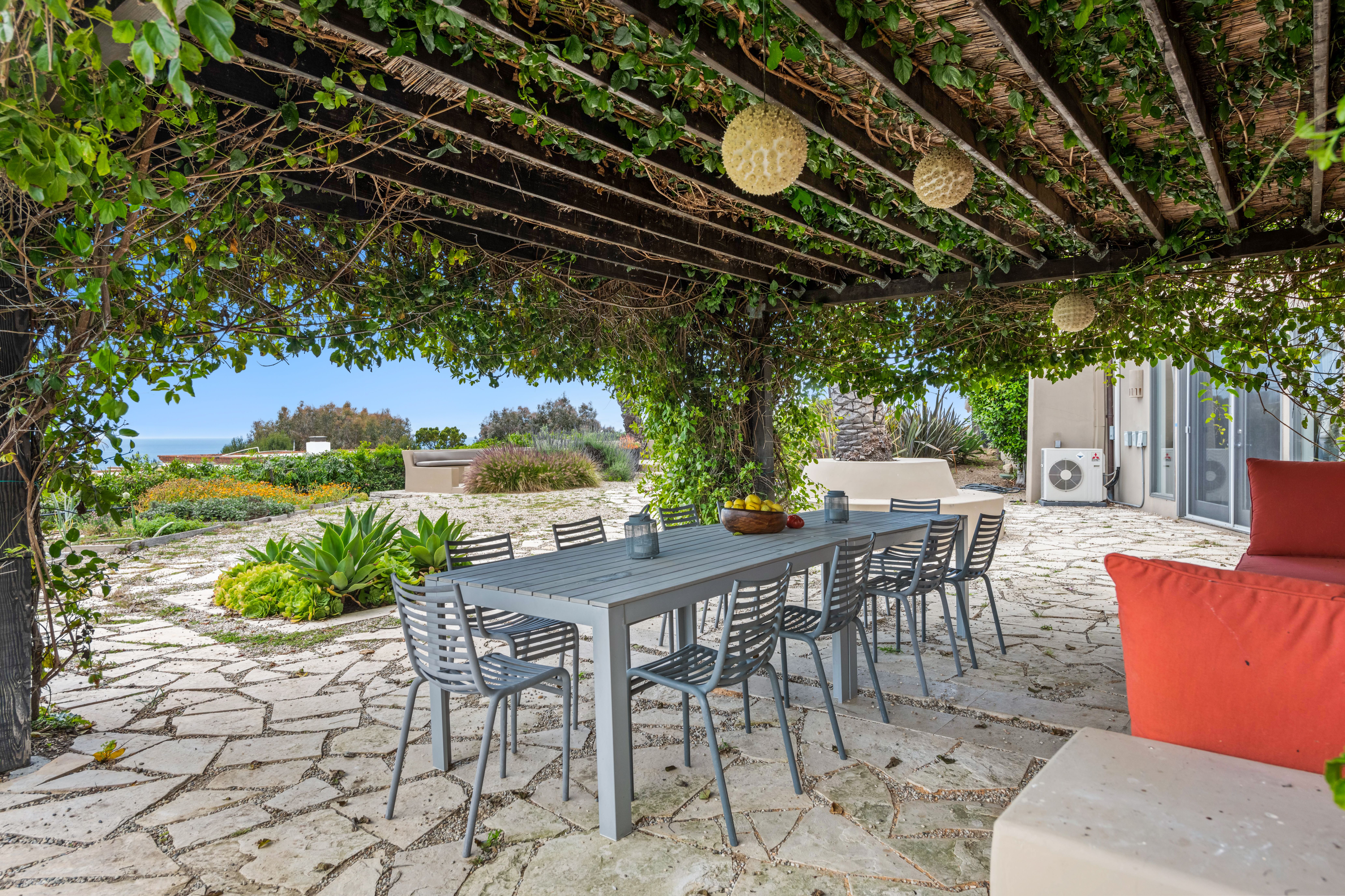 Garden patio dining setup under a vine-covered pergola for a secluded outdoor meal
